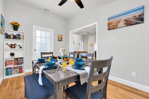 A dining area with a table set for four, surrounded by chairs, with a bookshelf and a painting on the walls. - Pool, Fire Pit, Near Beaches | Sleeps 9, Dogs OK (Largo)