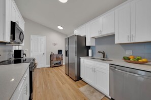 A modern kitchen with white cabinets, stainless steel appliances, and a wooden floor. - Pool, Fire Pit, Near Beaches | Sleeps 9, Dogs OK (Largo)