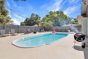 A backyard with a swimming pool, lounge chairs, a barbecue grill, and a wooden fence. - Pool, Fire Pit, Near Beaches | Sleeps 9, Dogs OK (Largo)