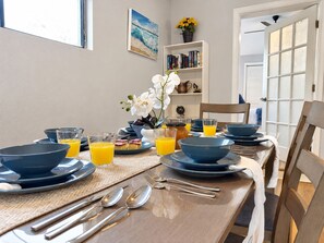 Une table à manger dressée avec de l’argenterie, des assiettes bleues et des verres remplis de jus d’orange.