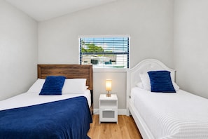 A hotel room with two beds, a nightstand with a lamp, and a window with blinds. - Pool, Fire Pit, Near Beaches | Sleeps 9, Dogs OK (Largo)