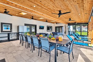 Eine moderne Küche mit Essbereich, Fernseher und Sitzgelegenheit am Pool.