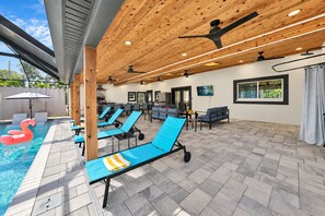 Ein Poolbereich mit Liegestühlen, einem Schwimmbecken und Deckenventilatoren.