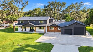 Ein modernes, zweistöckiges Haus mit überdachter Terrasse, Garage und gepflegtem Rasen.