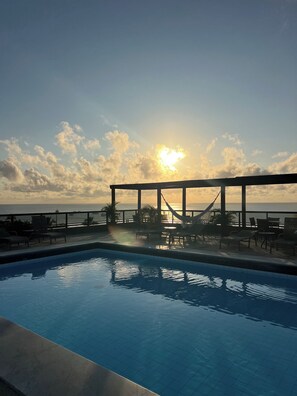Ein Pool mit Blick auf den Ozean und einen Sonnenuntergang.
