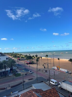 Blick auf einen Strand mit einer Straße, Fahrzeugen und Strand.