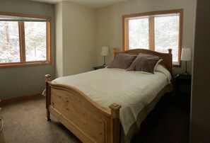 A bedroom with a wooden bed, two bedside tables with lamps, and two windows with blinds. - Great Location. On bus route with private hot tub. Sleeps 9. Great, comfy place! (Breckenridge)