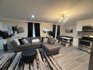 A modern living room with a sectional sofa, ottoman, and a dining area with a bench. - Cozy 1-bedroom apartment in delightful Jonesboro with AC (Jonesboro)