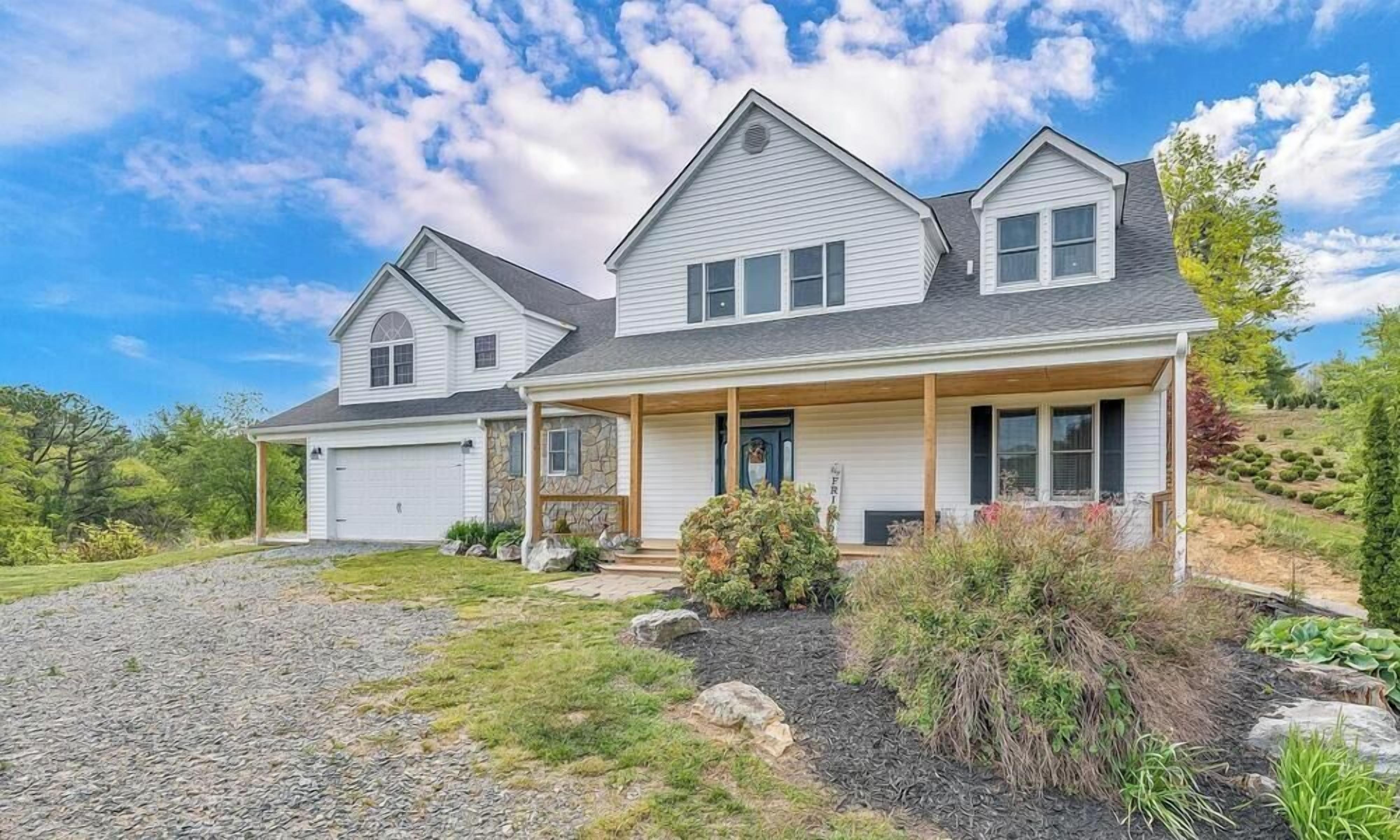 A two-story house with a covered porch, a garage, and a landscaped front yard.