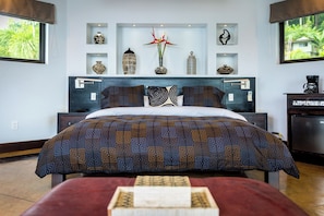 Un dormitorio con una cama grande, una mesita de noche, un aparador y objetos decorativos en estantes.