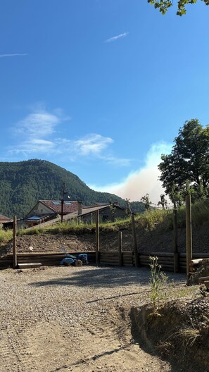 A rural setting with a gravel driveway, a blue tractor, and traditional buildings with sloped roofs.