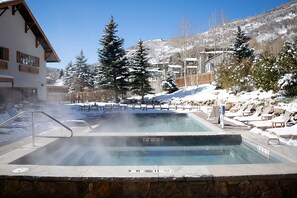 Ein Bereich mit Whirlpool, Steinwand, Liegestühlen und Pool.