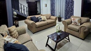 A modern living room with two sofas, a coffee table, and a staircase leading to another level.