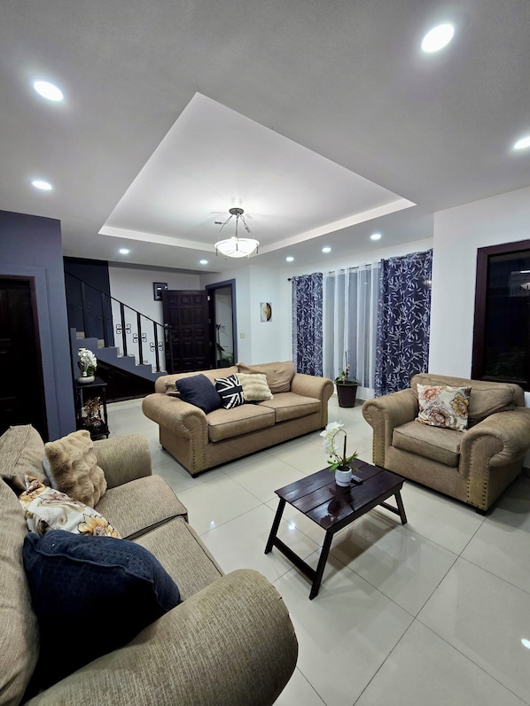 A modern living room with two sofas, a coffee table, and a staircase leading to another level.