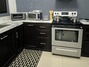 A kitchen with a microwave, toaster, stove, and oven. - Casa Moderna con Piscina Privada en el corazón de Santa Rosa de Copán (Santa Rosa de Copán)