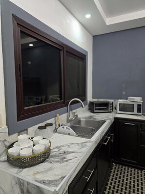 A kitchen with a marble countertop, a sink, a window, and a microwave. - Casa Moderna con Piscina Privada en el corazón de Santa Rosa de Copán (Santa Rosa de Copán)