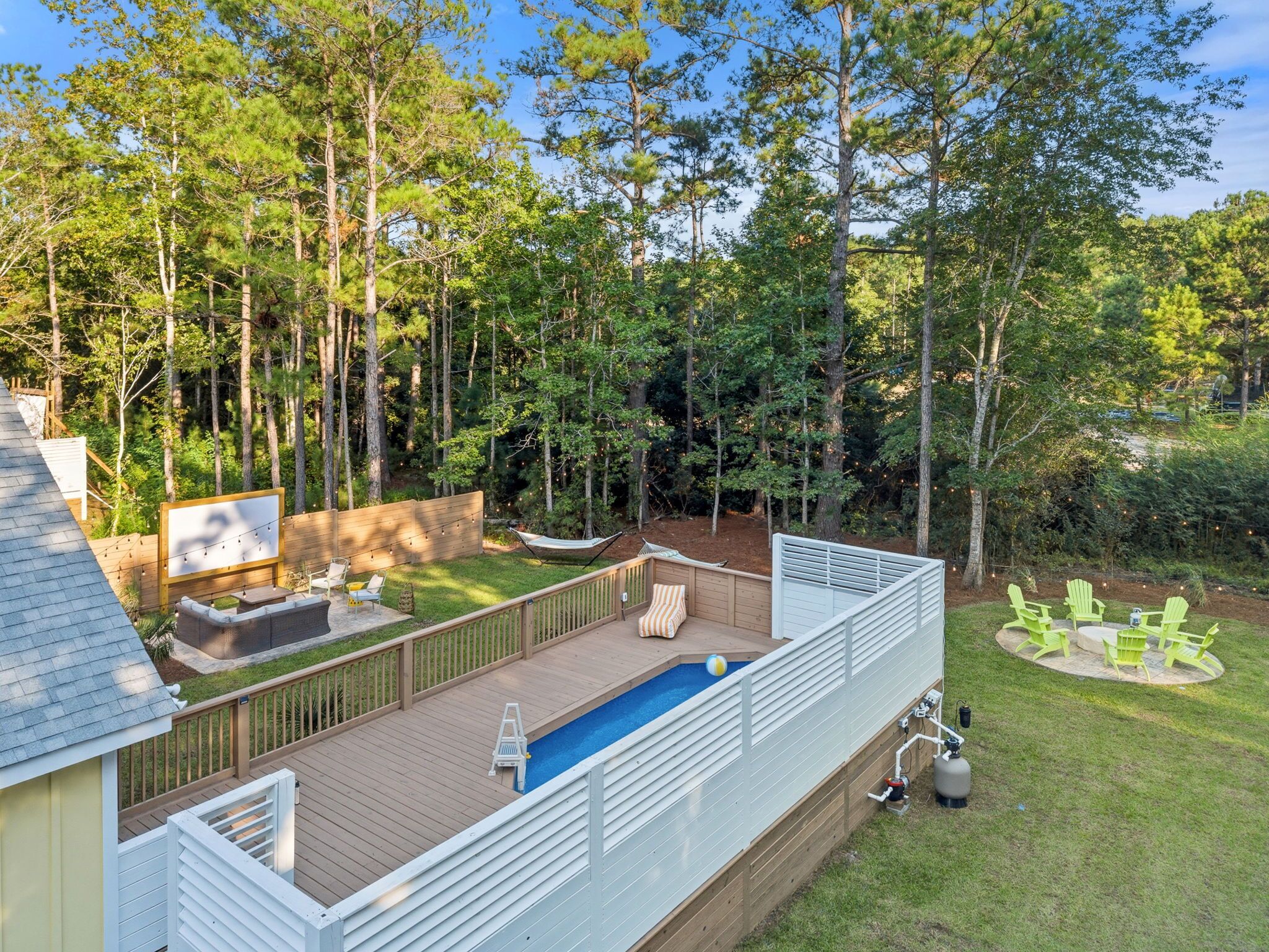 Un jardin avec une piscine, une terrasse et un espace salon extérieur.