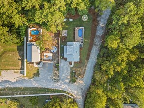 An aerial view of a residential property with a swimming pool, a patio, and a garage.