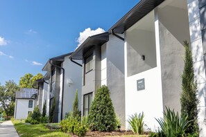 A modern building with a clean, white exterior and a small sign indicating the name and address. - One-Bedroom Suite w/ Living Room Near Orlando Fun (Orlando)