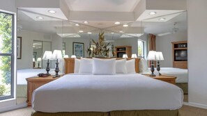 A large bed with white linens, two bedside tables with lamps, a large mirror above the bed, and a ceiling with recessed lighting. - One-Bedroom Suite w/ Living Room Near Orlando Fun (Orlando)