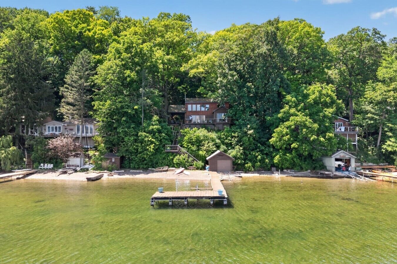 A lakeside property with a dock, a small shed, and a house surrounded by dense trees.