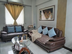 A living room with two sofas, a glass coffee table, and a framed picture on the wall. - Manila Airport Budget Stays (Pasay City)