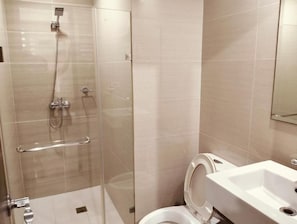 A modern bathroom with a glass-enclosed shower, a white sink, and a toilet. - Manila Airport Budget Stays (Pasay City)