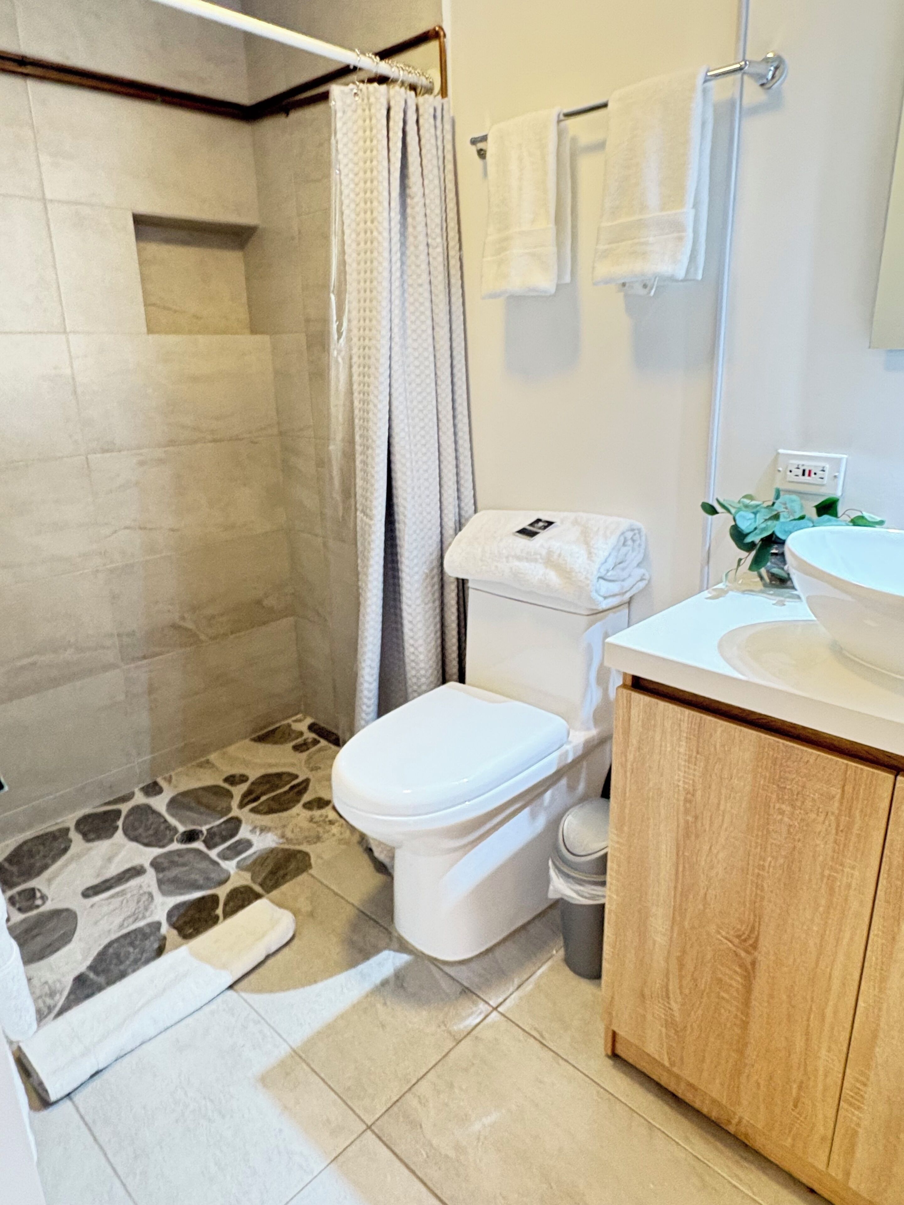 Ein Badezimmer mit Dusche, Toilette, Waschbecken und Spiegel.
