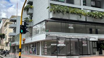 A modern building with multiple signs advertising real estate services, a pedestrian crossing, and a traffic light.
