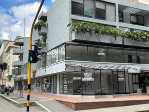 Un edificio moderno con varios letreros publicitarios de servicios de bienes raíces, un paso de peatones y un semáforo.