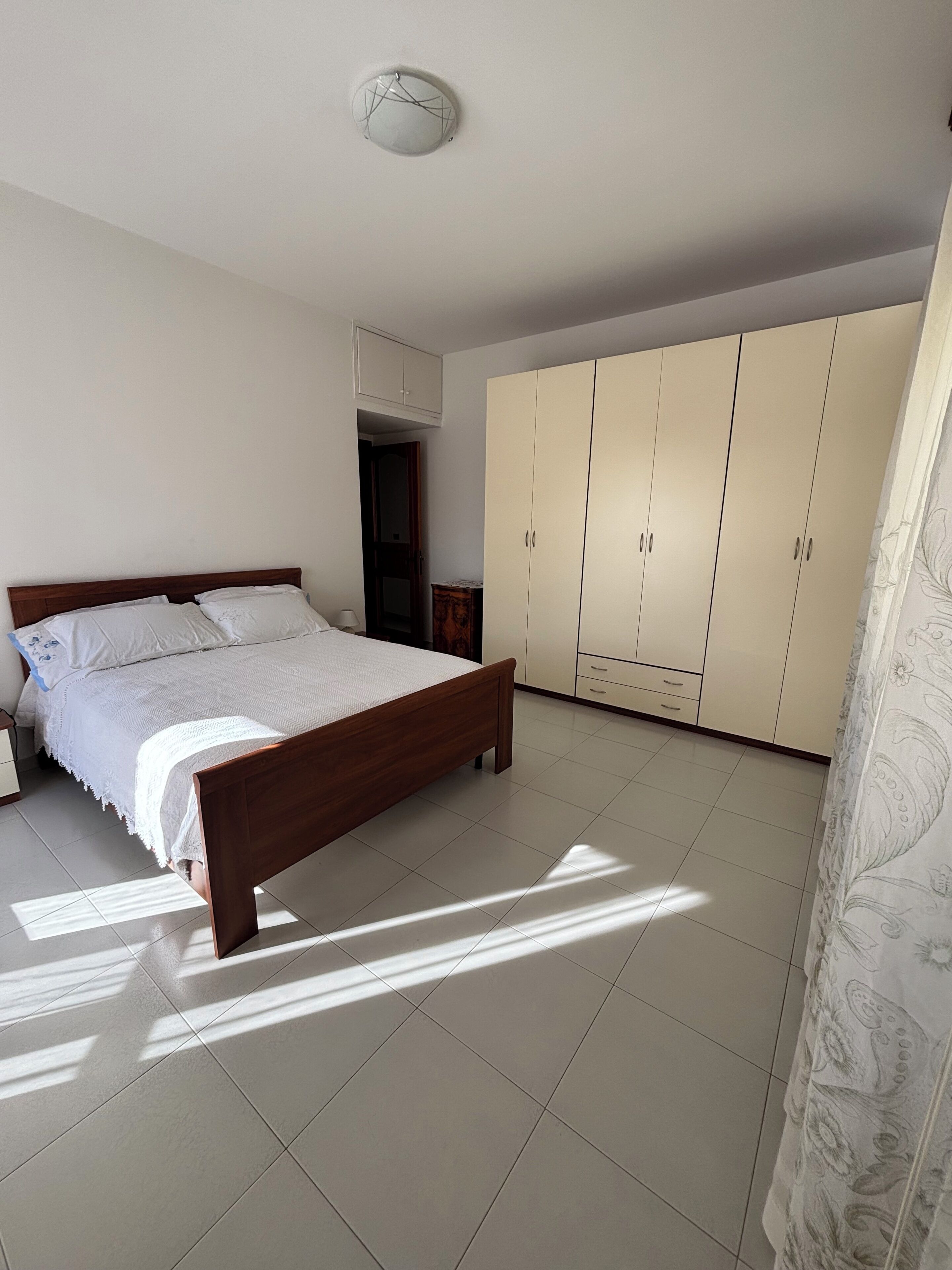 Een slaapkamer met een houten bed, een kledingkast en een plafondlamp.