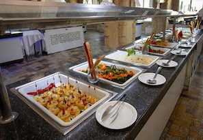 A buffet with various food items and utensils.