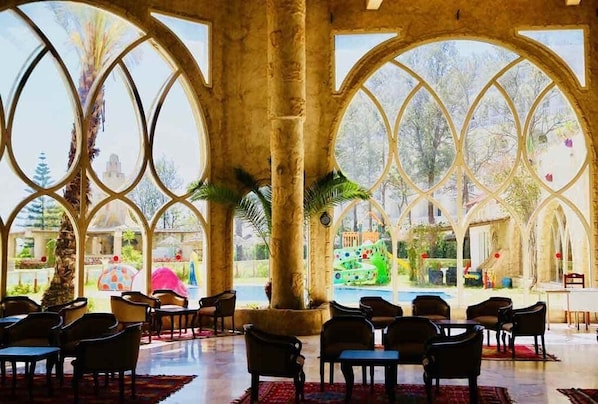 A spacious interior with large arched windows, a pool, and outdoor seating.