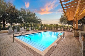 A rectangular swimming pool with a wooden pergola overhead, surrounded by lounge chairs and a brick patio. - Sun Deck | Communal Pool Access (Inlet Beach)