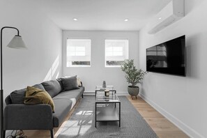 A modern living room with a sofa, coffee table, and a potted plant. - Newly Renovated Apartment in Chinatown (Ottawa)