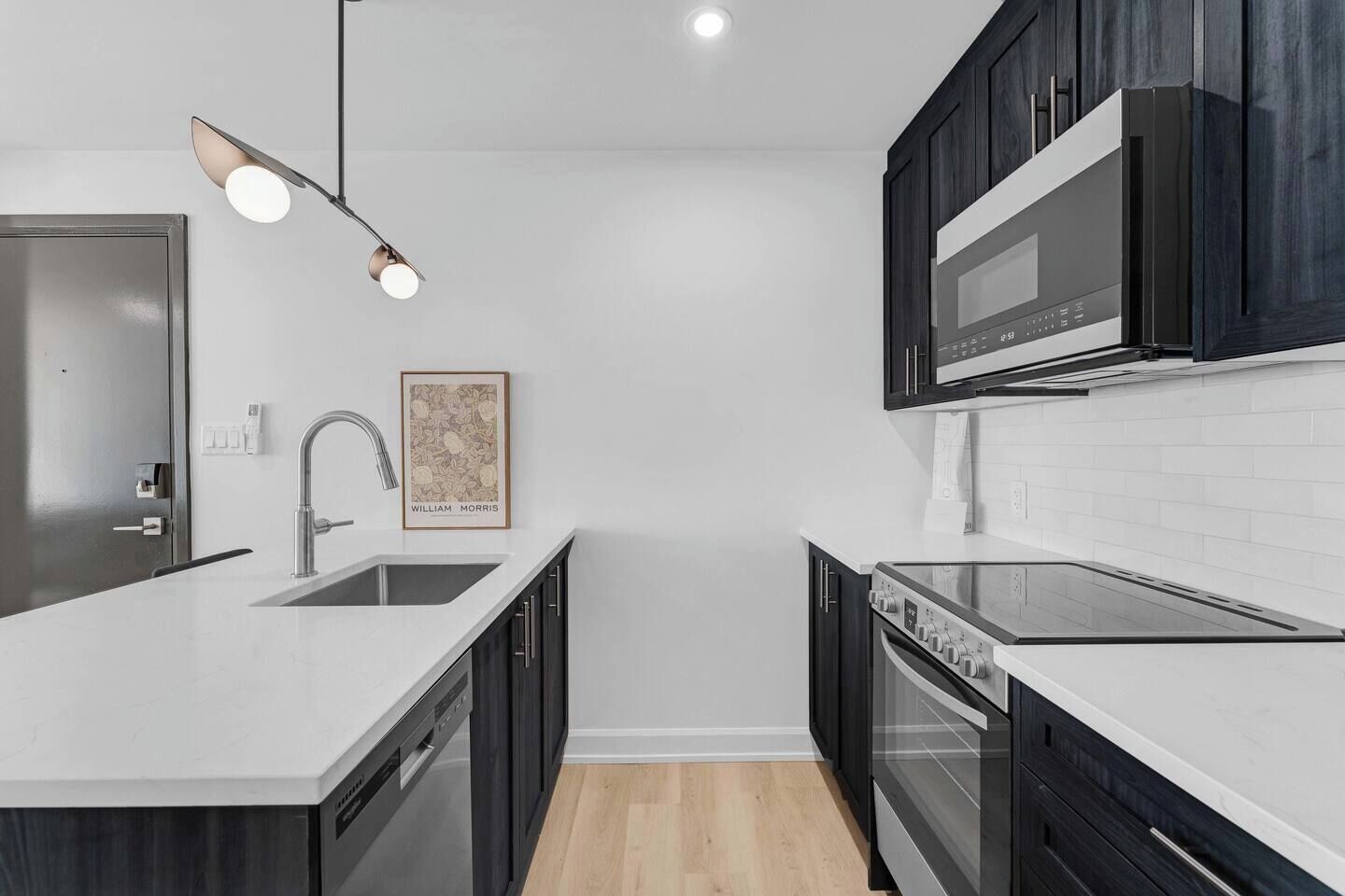 A modern kitchen with a central island, stainless steel appliances, and dark cabinetry.