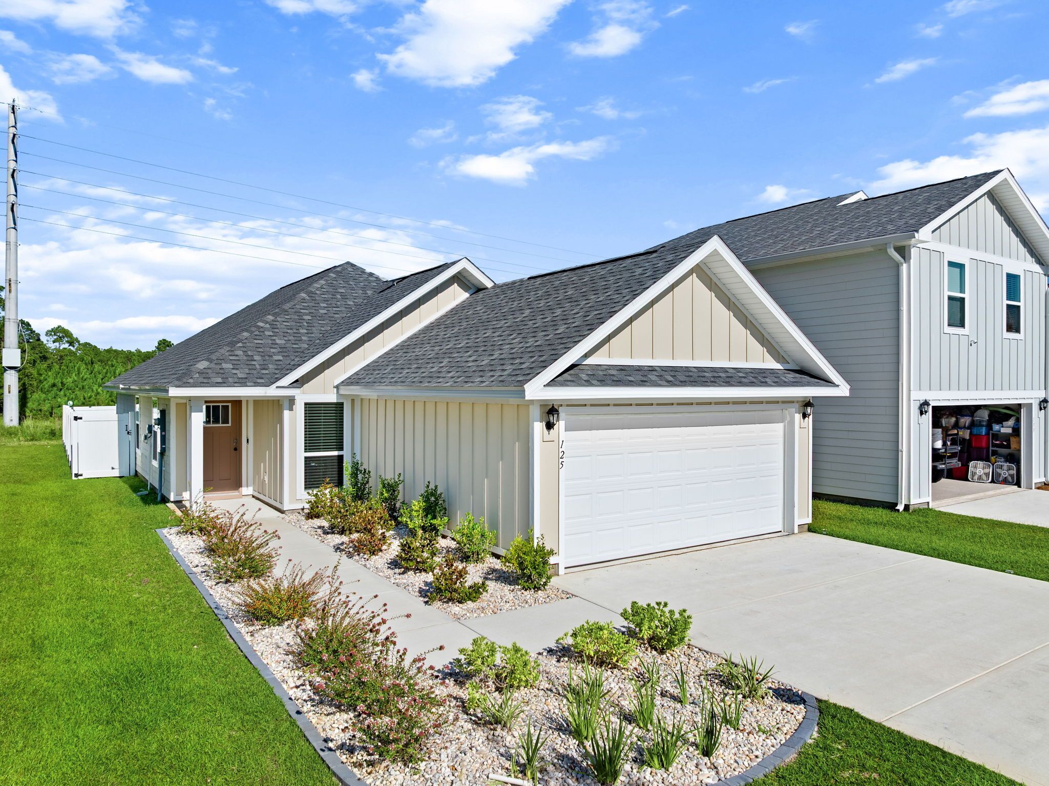 A residential property with a two-car garage, a covered driveway, and a landscaped front yard.