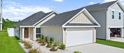 A residential property with a two-car garage, a covered driveway, and a landscaped front yard.