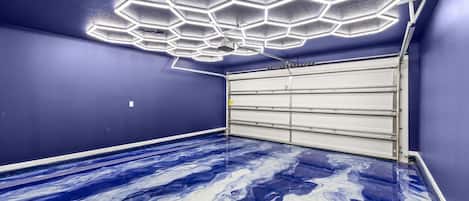 A garage with a blue floor and a ceiling with hexagonal light fixtures.