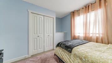 A bedroom with a bed, a wardrobe, and a window with curtains.