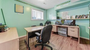 Una habitación con escritorio, silla, estanterías llenas de libros, una ventana y un calendario de pared.