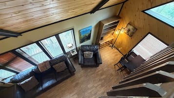 A wooden interior with a leather sofa, a dining table, and a staircase.