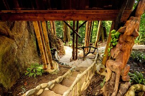 A stone staircase leading up to a wooden structure surrounded by bamboo and foliage. - Toucan's Nest Treehouse. Sleep in the canopy where rainforest meets the Ocean (Savegre de Aguirre, Puntarenas Province)