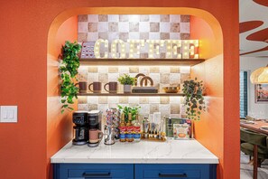 Eine Küche mit einer Kaffeestation, darunter eine Kaffeemaschine, Tassen und Torani-Sirups.