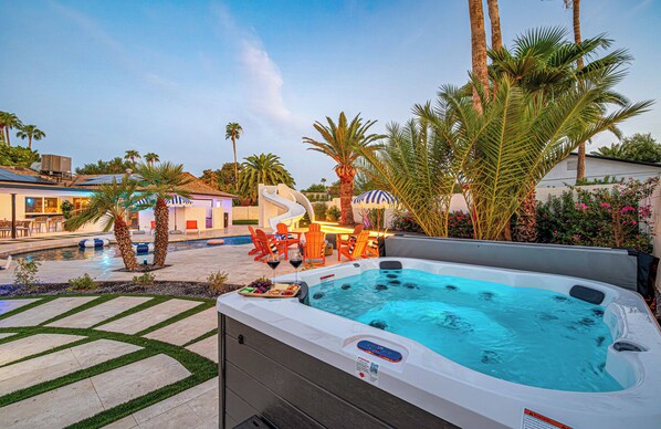 Ein Whirlpool mit Pool, Sitzgelegenheit im Freien und Palmen.