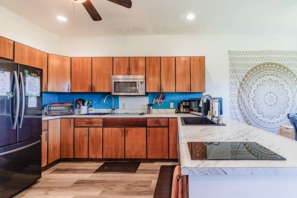 Una cocina moderna con armarios de madera, un refrigerador de acero inoxidable, un microondas y un lavamanos.