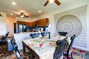 Una cocina moderna con armarios de madera, una mesa de comedor con sillas y un ventilador de techo.