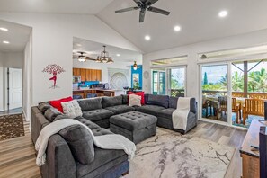 A spacious living area with a sectional sofa, a dining table, and a balcony with a view.