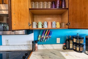 A kitchen with wooden cabinets, a blue backsplash, and various kitchen utensils and spices.