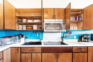 Una cocina con armarios de madera, un microondas, un lavaplatos y diversos utensilios de cocina.